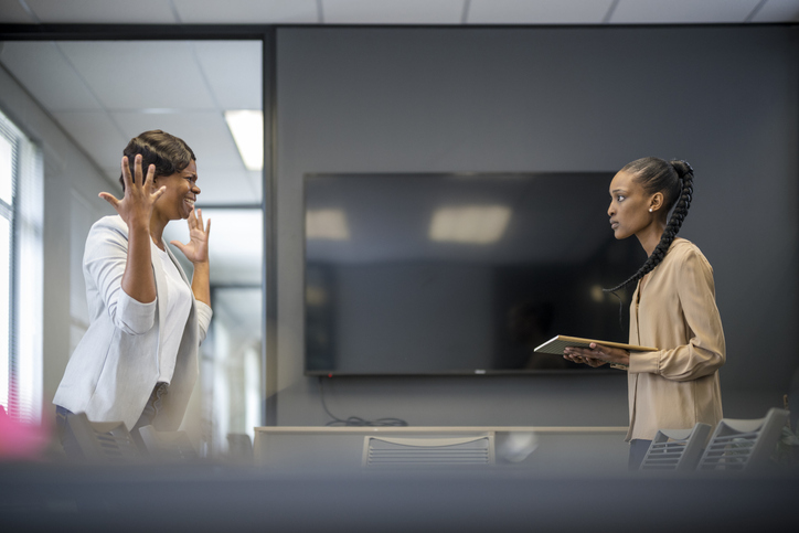 Female boss shouting at employee in boardroom