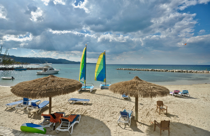 Lounge chairs and catamarans sit empty and unused on a cloudy day at the beach at a honeymoon destination
