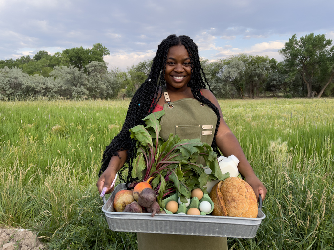 Portrait of a Happy Young African American Woman Standing at the Door of a Walk-In Refrigerator Holding a Basket of Delicious, Healthy, Organic Produce at a Local Small Business Farm-to-Table Supplier in Colorado