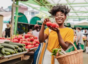 Portrit of a young African woman holding tomatoes at the farmers market