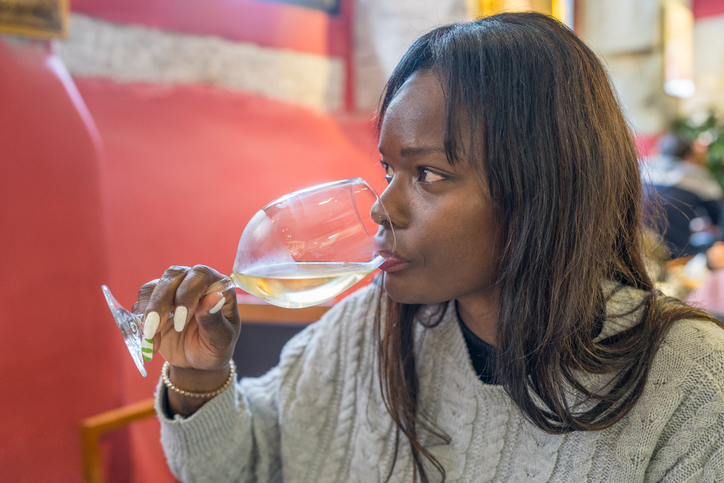 Woman enjoying drinking a cup of wine while sitting in a restaurant.