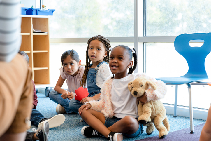 Kindergarten students listen to teacher read book