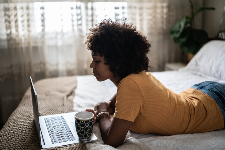 Young woman using the laptop on the bed at home