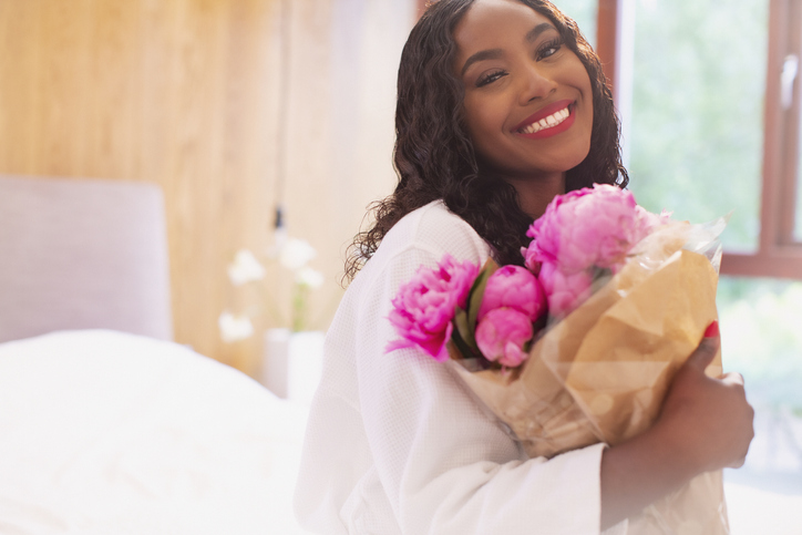Portrait happy young woman with bouquet of pink peony flowers