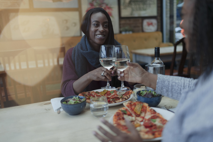 Mother and daughter enjoying wine and pizza at restaurant lunch