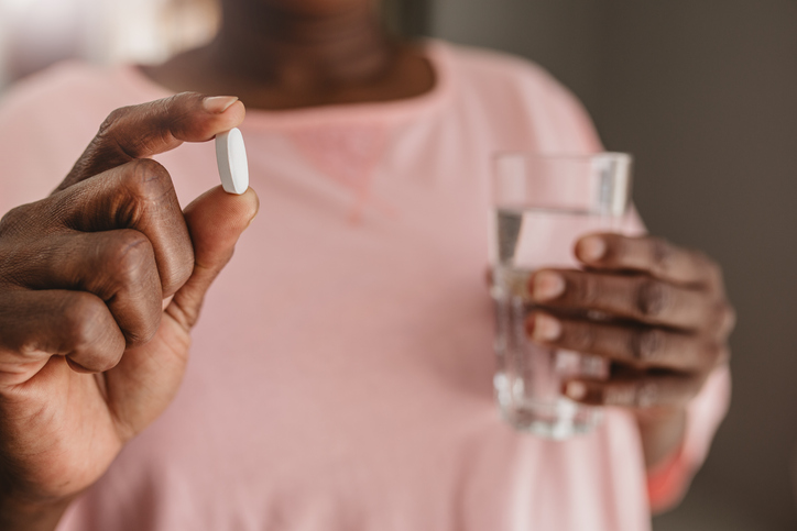 African American woman abaout to take a vitamin supplement