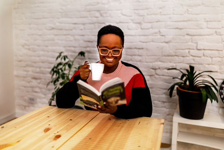 Afro-American black woman reading a book at home by a queer black author