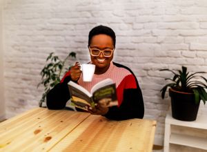 Afro-American black woman reading a book at home by a queer black author