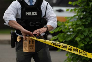 A police officer pulls police tape after a shooting in a...