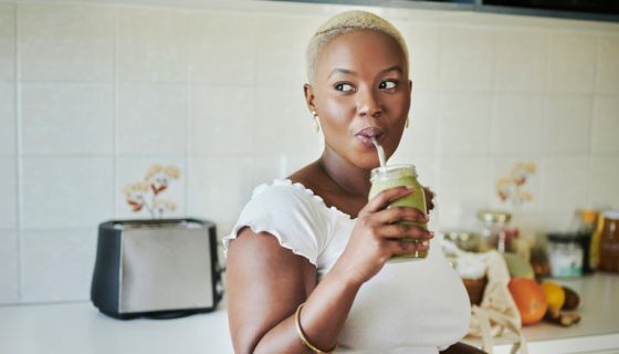Young African woman drinking on a smoothie with a reusable straw trying internal shower trend