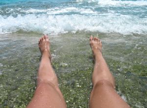 female legs on the beach on sea waves background