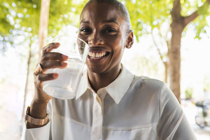 Businesswoman smiling while drinking hydrating beverages