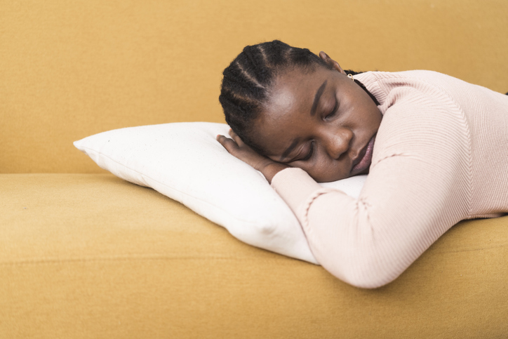 Portrait of a young Afro woman napping on the sofa due to sore throat
