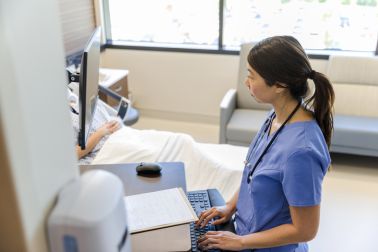 Female doctor works quietly on computer while patient rests