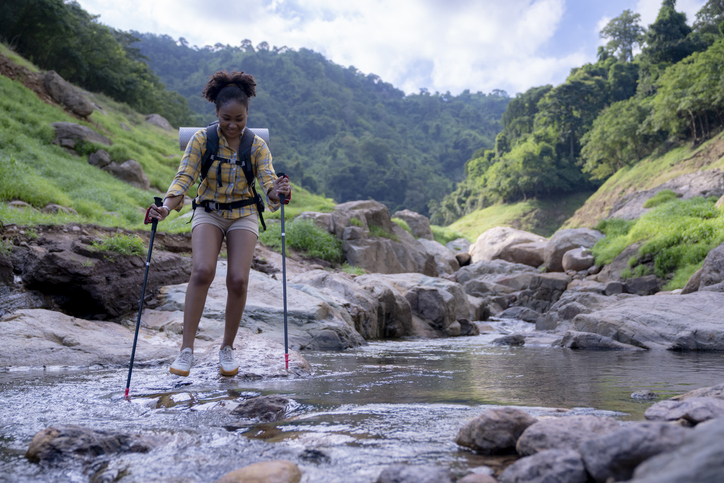 happy female hiking with trekking pole in the nature travel