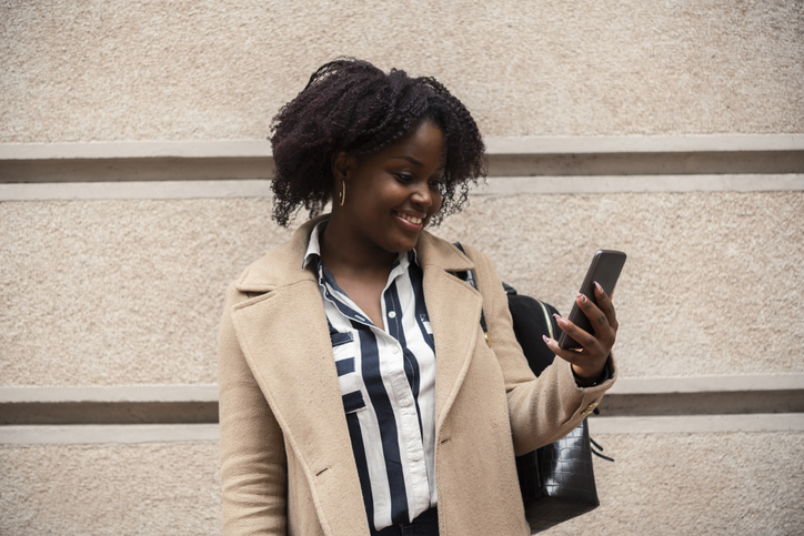 African American young woman using smartphone on the street