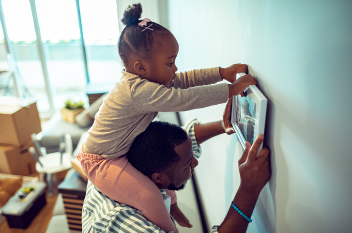 Father and daughter putting up paintings in their new home