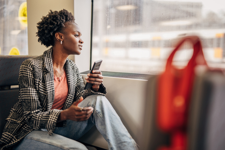 Young black woman suing smartphone in the train