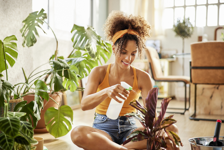 Woman Spraying Water On Plants While Sitting
