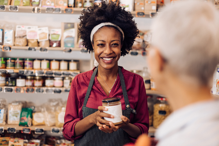 Afro saleswoman working with a customer at the reopened healthy food store