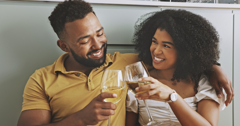 African couple toasting with wine glasses. Young in love man and woman clinking champagne glass, celebrating relationship anniversary. Two people dating and spending romantic valentines day together