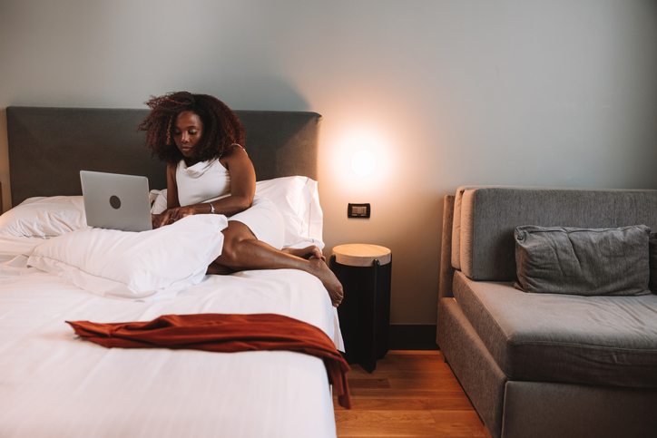 Businesswoman working on laptop on the bed of her hotel room