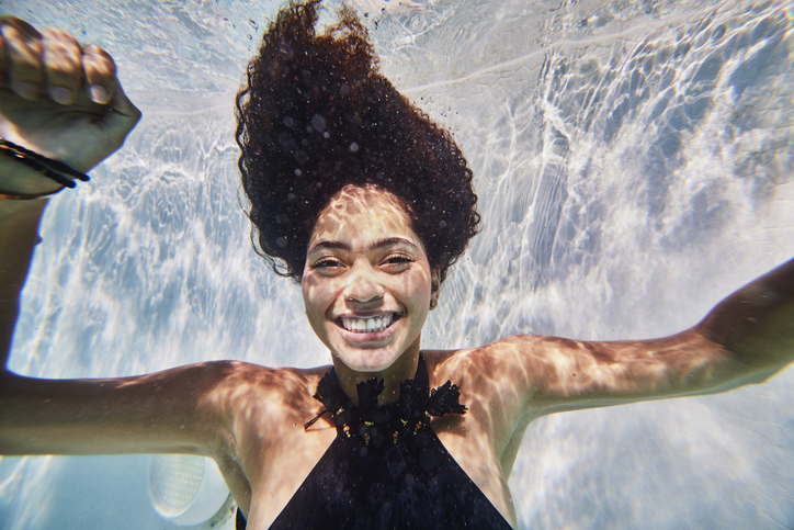 Medium shot of smiling woman underwater in pool while on vacation