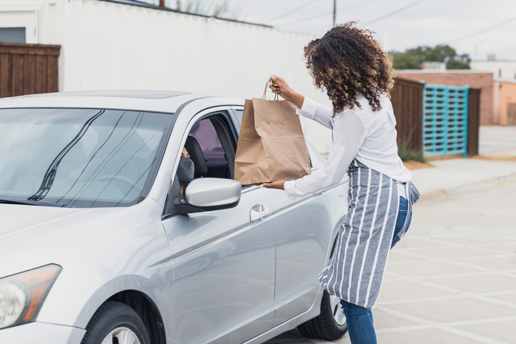 Waitress in apron delivers curbside meal