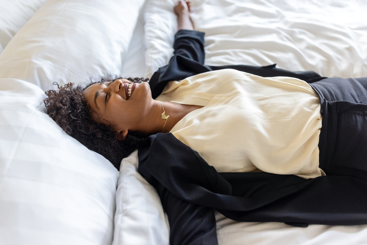 Exhausted businesswoman lying on hotel room bed