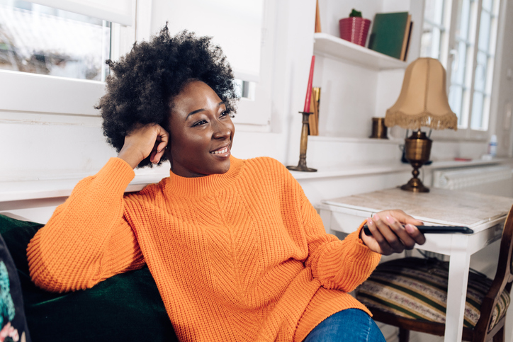 Portrait of a happy Afro woman watching TV and enjoying