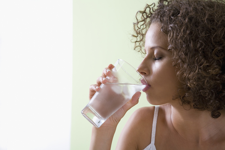 Mixed race woman drinking glass of water