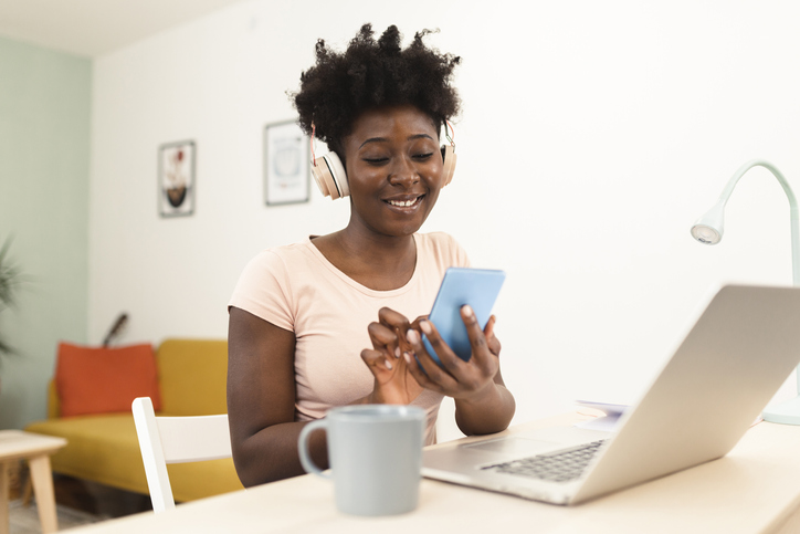 Portrait of a happy Afro woman working online and texting