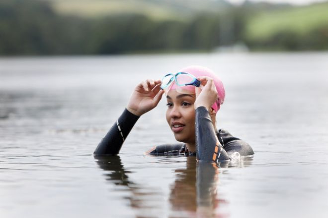 woman swimming in lake wearing wetsuit