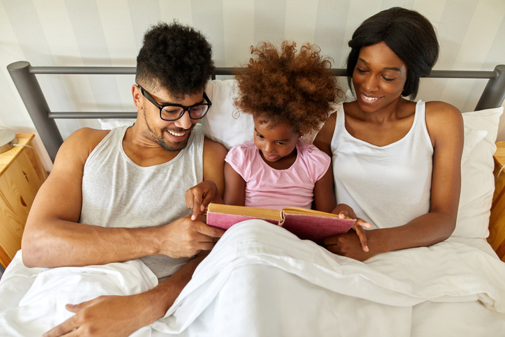 Happy family reading an interesting book in bed