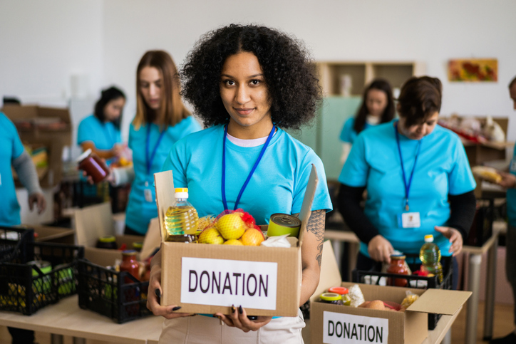 Portrait of a volunteer holding a food box for donation