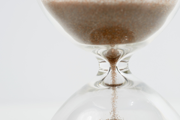 Close up of sand flowing through an hourglass.