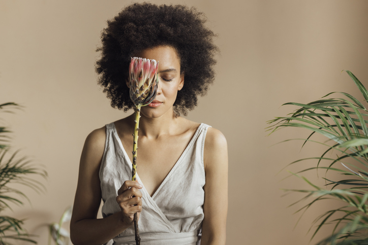A Beautiful Woman Holding A Tropical Flower And Enjoying Its Fragrance With Her Eyes Closed