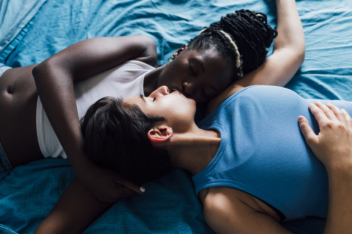 Young woman with eyes closed kissing girlfriend on bed