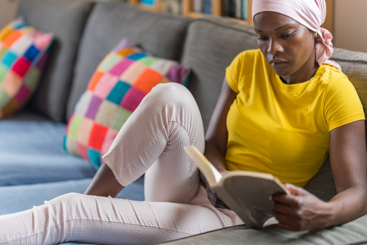 Close-up of a serious woman with ovarian cancer sitting while reading a book