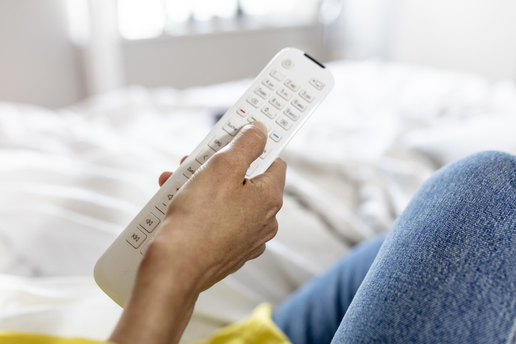 woman is using a remote control in her bed room