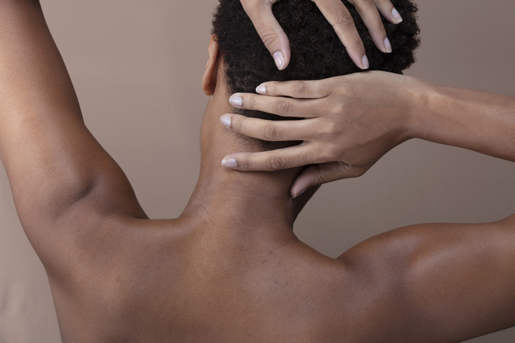 Rear view of shirtless woman touching head