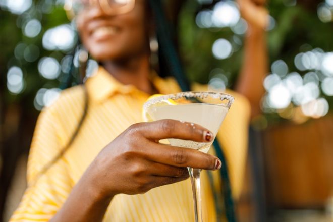 Close up shot of cheerful young woman enjoying a margarita cocktail