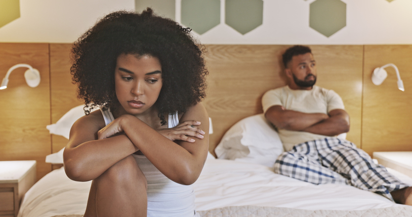 Unhappy male and female having relationship problems and about to breakup. African American couple angry at each other in the morning and sitting in a bedroom. Young upset couple avoiding each other, grown men, childish, immature 