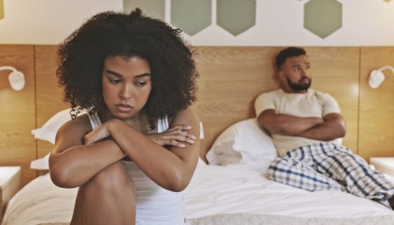 Unhappy male and female having relationship problems and about to breakup. African American couple angry at each other in the morning and sitting in a bedroom. Young upset couple avoiding each other, grown men, childish, immature
