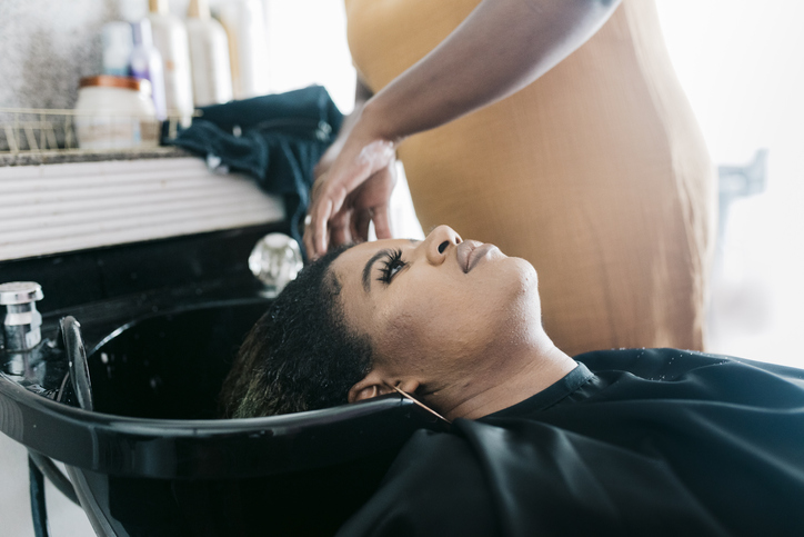 Black Client Leaning Back While Getting Hair Washed At A Salon