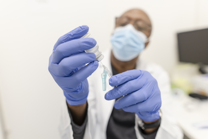 Close up doctor in rubber gloves and mask preparing vaccination