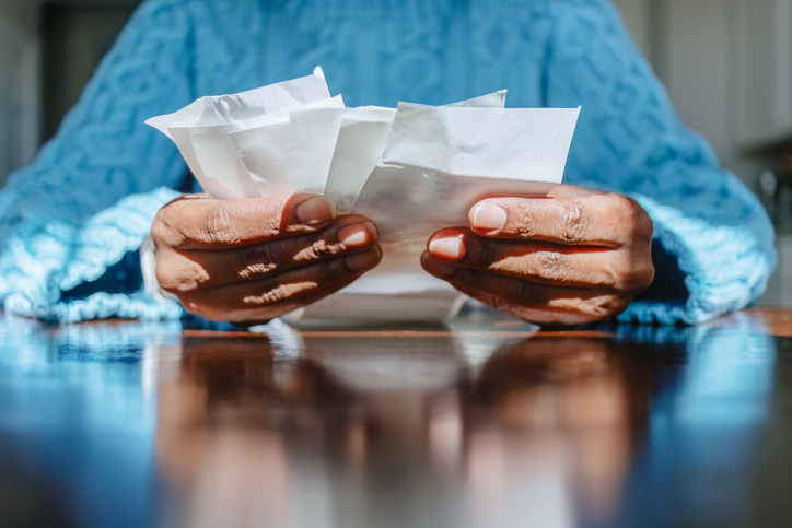 Woman Reviews Receipts at Kitchen Table