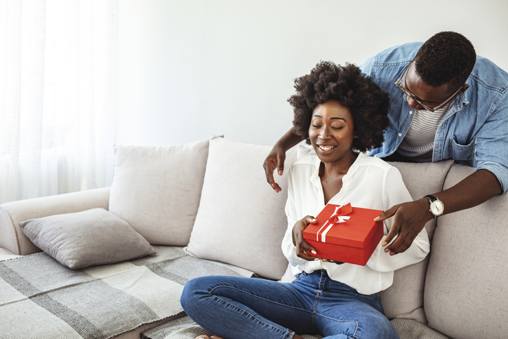 Cheerful young woman receiving a gift from her boyfriend expressing their love languages
