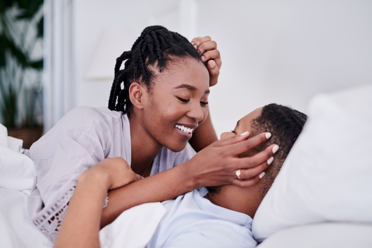 Shot of a young couple lying on their bed at home and enjoying a romantic moment together enjoying cbd products