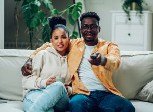 Multiracial couple watching television together at home on the couch involved in serial monogamy
